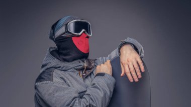 Bir snowboard portresi extream snowboard snowboard bir stüdyoda ile poz tam koruyucu giysiler giymiş. Gri bir arka plan üzerinde izole.