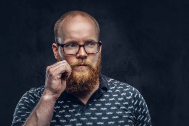 Kızıl saçlı sakallı erkek portresi bir t-shirt bıyığının üzerinde bir el ile poz içinde giyinmiş. Karanlık dokulu bir arka plan üzerinde izole.