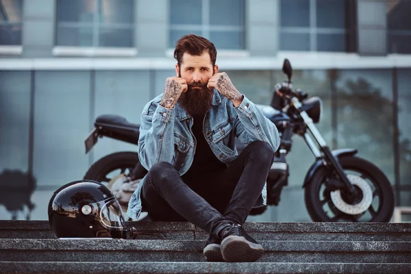 남자의 청바지 콧수염 마천루에 복고풍 오토바이 근처에 앉아있는 — 스톡 사진