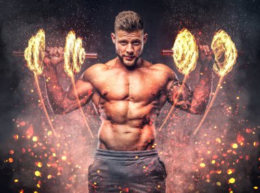 Dumbbells ile egzersizleri yapıyor güçlü şık vücut geliştirmeci, kolundaki dövme ile. Yangın sanat kavramı.