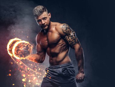 Bir pazı ile halter, tarih bak kendine güvenen bir bakışla kameraya yapıyor güçlü şık vücut geliştirmeci, kolundaki dövme ile. Yangın sanat kavramı.