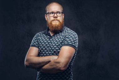 Kızıl saçlı sakallı erkek portresi t-shirt poz ile çapraz silah giyinmiş. Karanlık dokulu bir arka plan üzerinde izole.