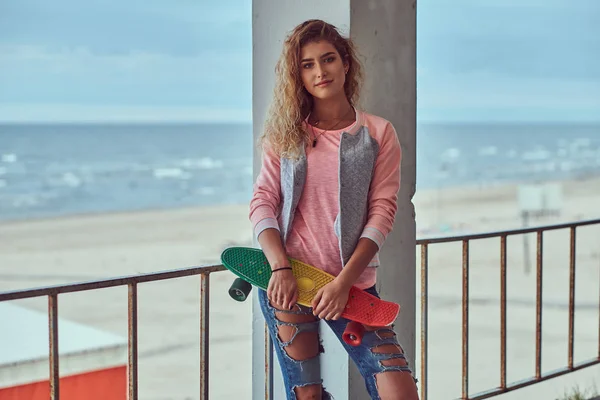 一个微笑的感性年轻女孩的肖像身着粉红色夹克 站在靠近海岸的护栏附近 — 图库照片