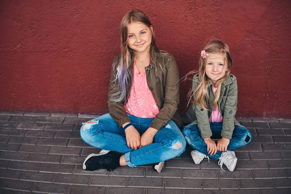 Portret Dwa Śliczne Małe Siostry Ubrana Modne Ciuchy Opierając Się — Zdjęcie stockowe