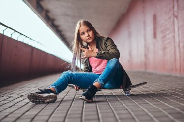 Bir köprü footway adlı bir kaykay üzerinde oturan trendy elbise giymiş sarışın kız öğrenci.