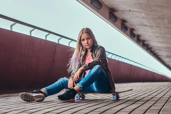 穿着时髦衣服的女学生坐在一座桥上的滑板上人行道 — 图库照片