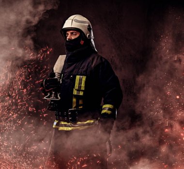 Tek tip tutar profesyonel bir itfaiyeci yangın hortumu ateşe kıvılcım ve karanlık bir arka plan üzerinde duman.