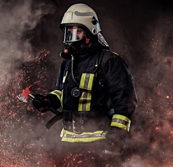 火の赤斧立って火花し 煙の暗い背景の上に保持している制服で酸素マスクを着て消防士 — ストック写真