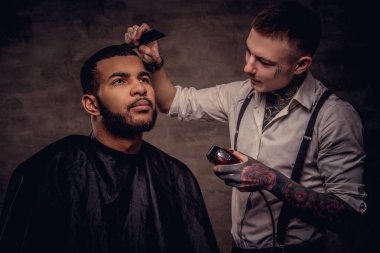 Sakallı Afro-Amerikan hipster adam bir saç kesimi tarafından bir eski moda tattoed profesyonel kuaför saç kesimi yapıyor.