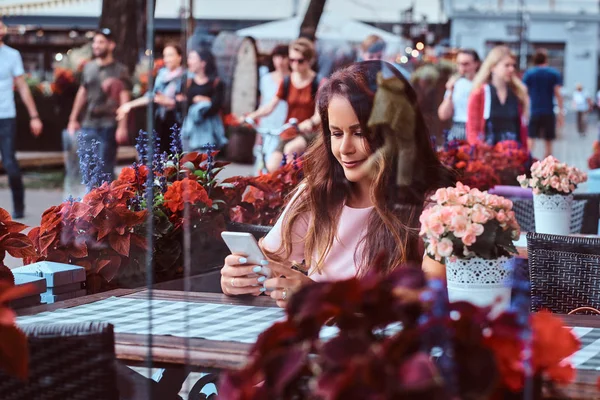 Uzun Kahverengi Saçlı Açık Kafede Otururken Bir Smartphone Kullanarak Bir — Stok fotoğraf