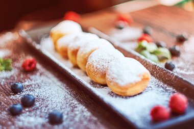 Yakın çekim fotoğraf kümesi Donuts ahududu bilberry ve nane ile siyah uzun tabakta pudra şekeri serpilir.