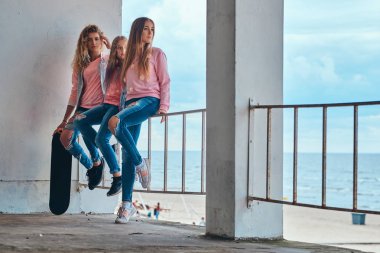 Üç kız kardeşim bir yalı karşı bir Otokorkuluk oturan trendy elbise giymiş portresi.