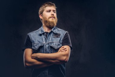 Yakışıklı hipster adam portresi karanlık bir arka plan üzerinde çapraz silah ile poz kot ceket giymiş.