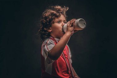 Spor bir altın madalya içme suyu bir şişe ile küçük şampiyon çocuk. Karanlık dokulu arka plan üzerinde izole.