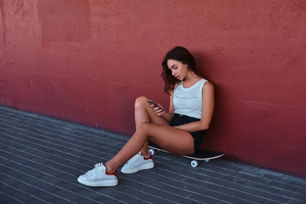 Retrato Hipster Sensual Sentado Skate Usando Smartphone Ouvindo Música Enquanto — Fotografia de Stock