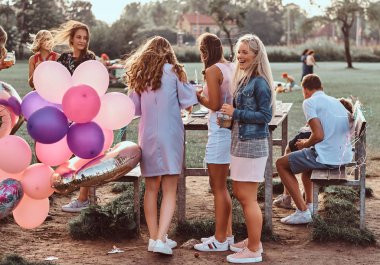 Mutlu kız konuşma piknik partide açık birlikte. Bir Doğum günü kutlamaları park açık sahne.