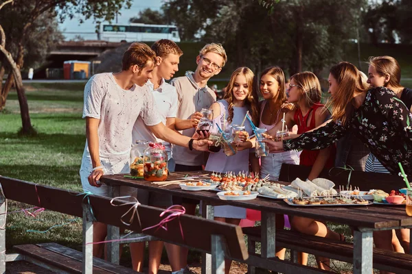 Група щасливих друзів розважаються разом, святкуючи день народження у відкритому парку. Радісні друзі вітають з соком на вечірці на відкритому повітрі . — стокове фото
