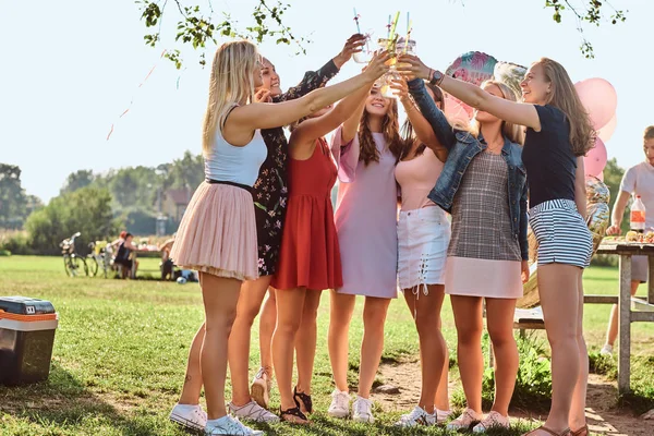 Група подружок розважається разом, святкуючи день народження у відкритому парку. Щасливі друзі вітають з соком на вечірці на відкритому повітрі . — стокове фото