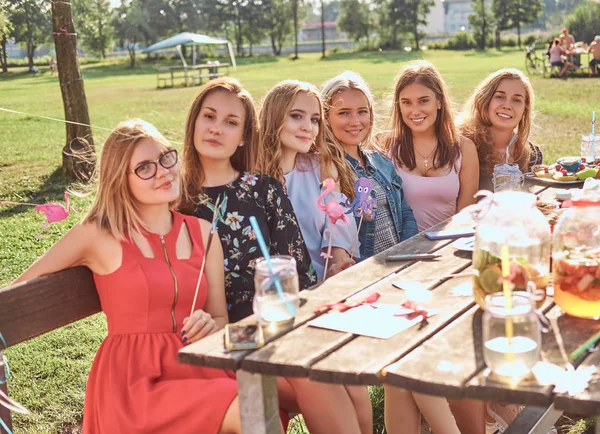 Groep van gelukkig vriendinnen zitten aan de tafel samen vieren van een verjaardag in het buiten park. — Stockfoto