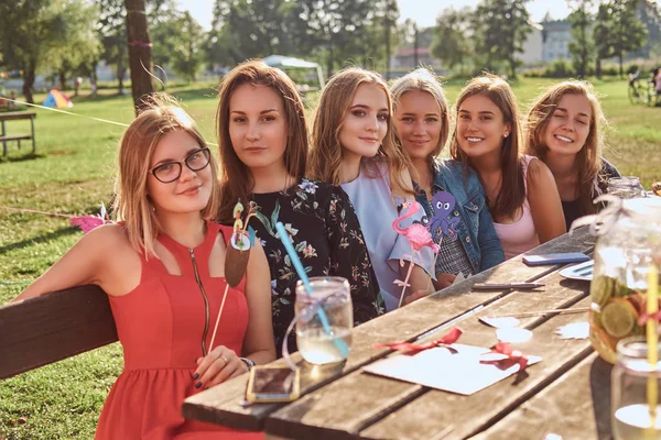 Grupo de amigas felices sentadas a la mesa juntos celebrando un cumpleaños en el parque al aire libre . —  Fotos de Stock