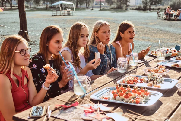 Grupo de amigas felices comiendo en la mesa juntos celebrando un cumpleaños en el parque al aire libre . — Foto de Stock