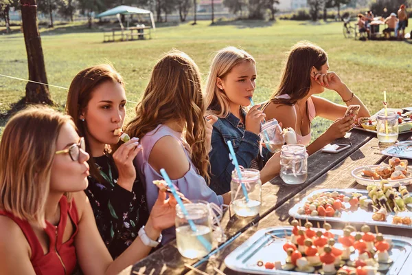 Група щасливих подруг, які їдять за столом разом, святкуючи день народження у відкритому парку . — стокове фото