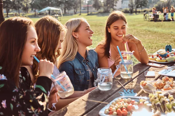 Група щасливих подруг, які сидять за столом разом, святкуючи день народження у відкритому парку . — стокове фото