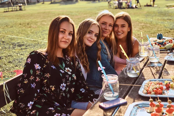 Grupo de amigas felices sentadas a la mesa juntos celebrando un cumpleaños en el parque al aire libre . —  Fotos de Stock