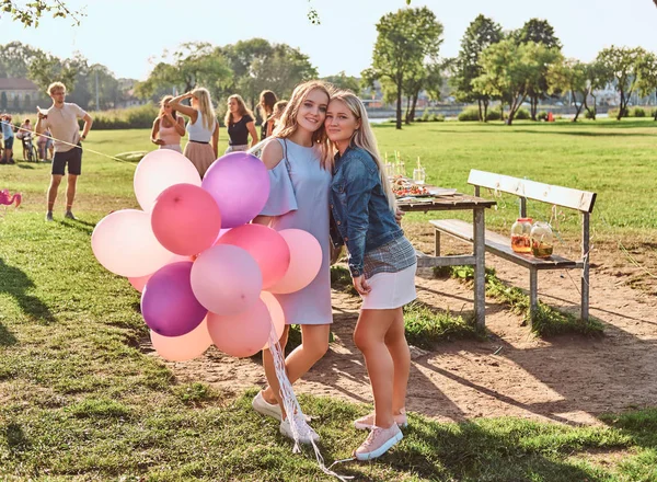 Усміхнені подружки позують з повітряними кулями біля столу, святкуючи день народження у відкритому парку . — стокове фото