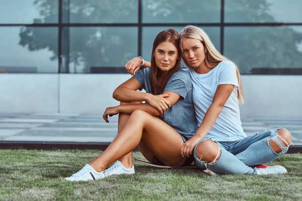 Duas Garotas Sorridentes Abraçando Enquanto Estavam Sentadas Skate Gramado Fundo — Fotografia de Stock