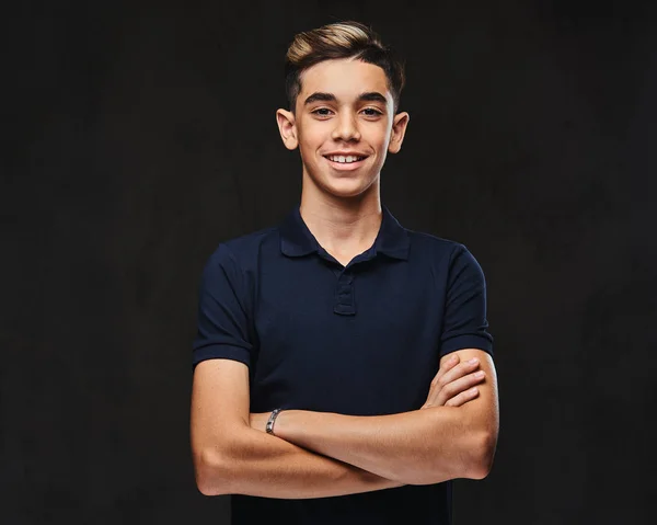 Handsome smiling young guy dressed in black t-shirt standing with crossed arms. Isolated on the dark background.