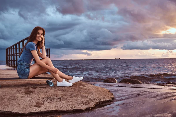 Усміхнена Чарівна Дівчина Сидить Скейтборді Пляжі Насолоджується Дивовижною Темною Хмарною — стокове фото
