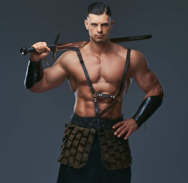 Brutal ancient Greece warrior with a muscular body in battle uniforms posing on a dark background clipart