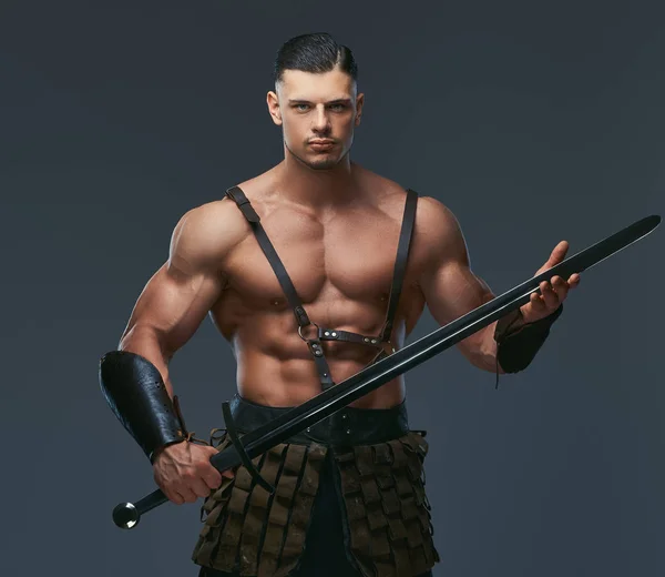 暗い背景にポーズの戦闘服で筋肉ボディを持つ残忍な古代ギリシャの戦士 — ストック写真