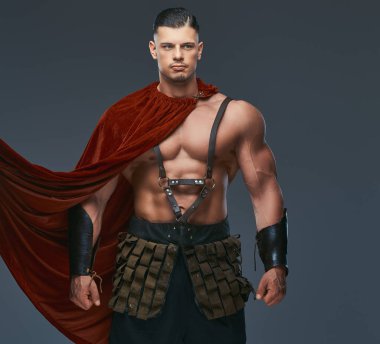 Gri bir arka plan üzerinde poz savaş üniformalı bir kas vücut ile acımasız Antik Yunanistan savaşçı.