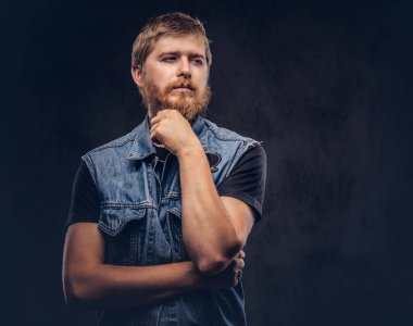 Dalgın hipster adam portresi çene üzerinde el ile poz kot ceket giymiş. Karanlık bir arka plan üzerinde izole.