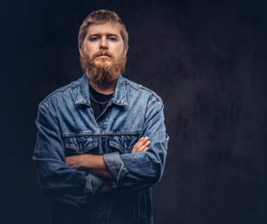 Yakışıklı hipster adam portresi ile çapraz kolları poz kot ceket giymiş. Karanlık bir arka plan üzerinde izole.