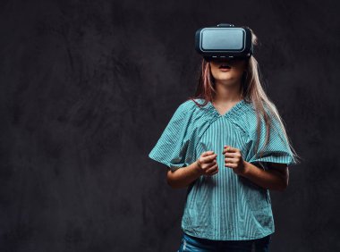 Genç kız sanal gerçeklik gözlükle rahat giyinmiş. Karanlık dokulu bir arka plan üzerinde izole.