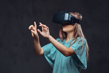 Genç kız sanal gerçeklik gözlükle rahat giyinmiş. Karanlık dokulu bir arka plan üzerinde izole.