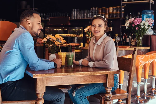 Feliz lindo casal afro-americano apaixonado ter um grande momento juntos em um restaurante em seu namoro, um casal atraente curtindo uns aos outros, segura óculos de suco . — Fotografia de Stock
