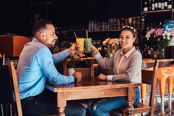 Glücklich schönes afrikanisch-amerikanisches verliebtes Paar, das beim Dating in einem Restaurant eine tolle Zeit miteinander verbringt, ein attraktives Paar, das sich gegenseitig genießt, hält ein Glas Saft in der Hand. — Stockfoto