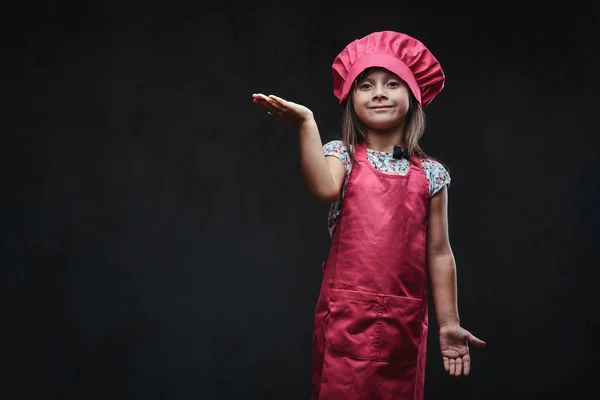 快乐的小女孩穿着粉红色的厨师摆在演播室 在深色纹理背景下隔离 — 图库照片