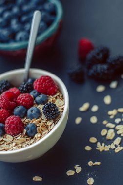 Sağlıklı kahvaltı. Beyaz tabak yulaf ezmesi mayınları ve mavi bir arka plan üzerinde farklı çilek ile.