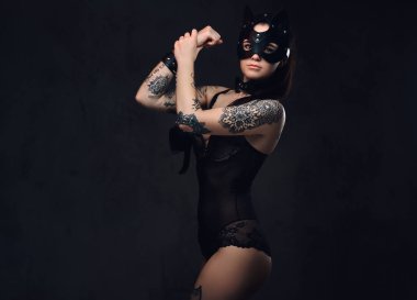 Bdsm aksesuarları ve karanlık bir arka plan üzerinde poz kedi deri maske siyah iç çamaşırı giyen baştan çıkarıcı şehvetli hanım kız. Karanlık bir arka plan üzerinde izole.   
