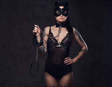 Bdsm kedi deri maske ve karanlık bir arka plan üzerinde poz aksesuarlar seksi siyah iç çamaşırı giyen güzel esmer kadın. 