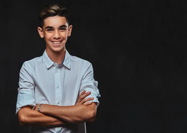 Happy young guy dressed in white shirt standing with crossed arms. Isolated on a dark background.