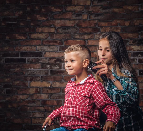 可爱的学龄后男孩得到理发 姐姐用一把修剪过的砖墙剪了她的小弟弟 — 图库照片