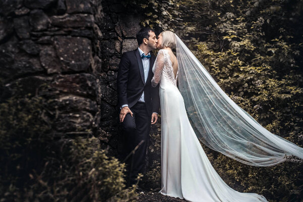 Lovely couple - bride and groom hugging and kiss at a beautiful mystery forest.