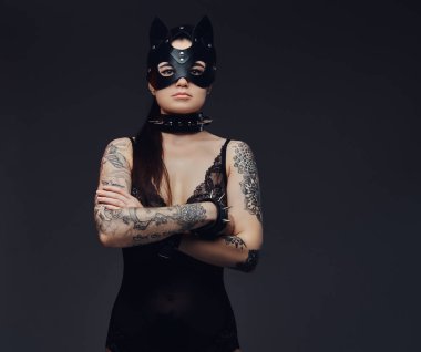 Bdsm kedi deri maske ve poz aksesuarlar seksi siyah iç çamaşırı giyen güzel esmer kadın kolları karanlık bir arka plan üzerinde geçti.. 