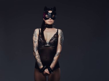 Bdsm kedi deri maske ve karanlık bir arka plan üzerinde poz aksesuarlar siyah iç çamaşırı giymiş seksi kadın. 